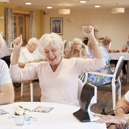 Senior Woman Winning Game Of Bingo In Retirement Home